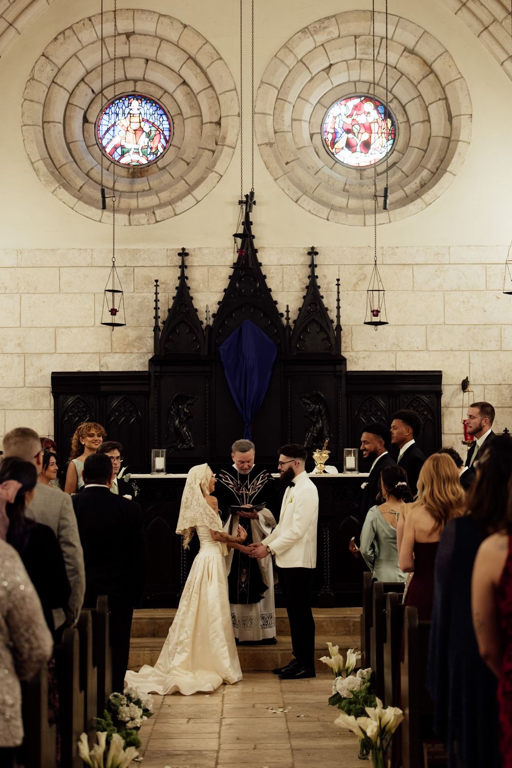 Wedding ceremony taking place in a grand church with gothic architecture and stained glass windows.
