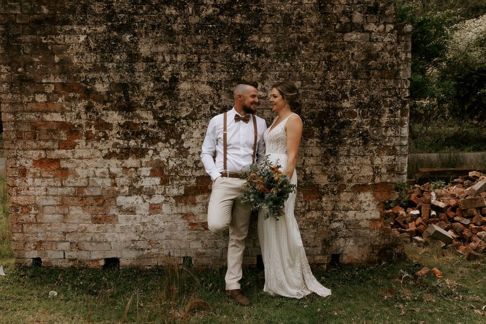 A couple in white wedding attire sits together on rustic brick steps during an intimate outdoor photo session.