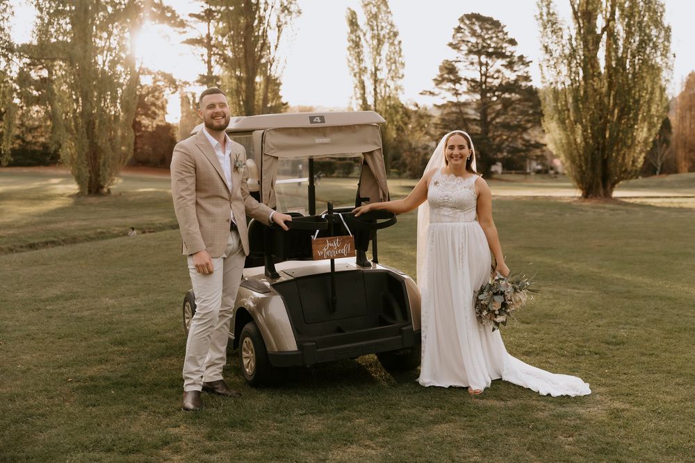A romantic wedding photoshoot at sunset with a vintage black truck in a rustic outdoor setting.