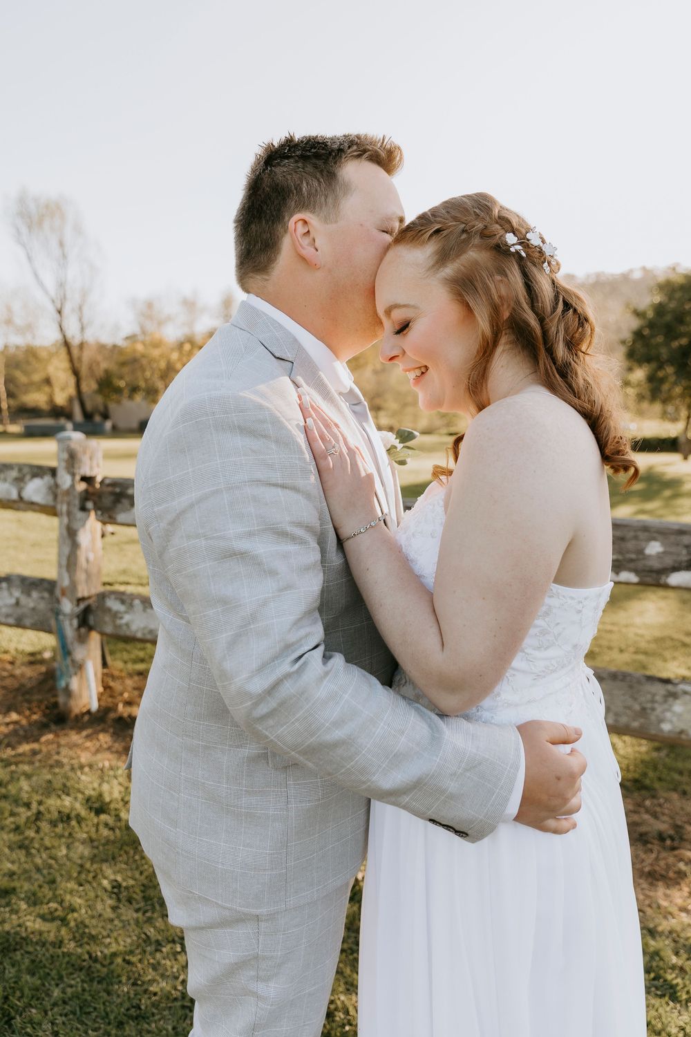 Intimate wedding couple embraces in a romantic outdoor setting during golden hour.