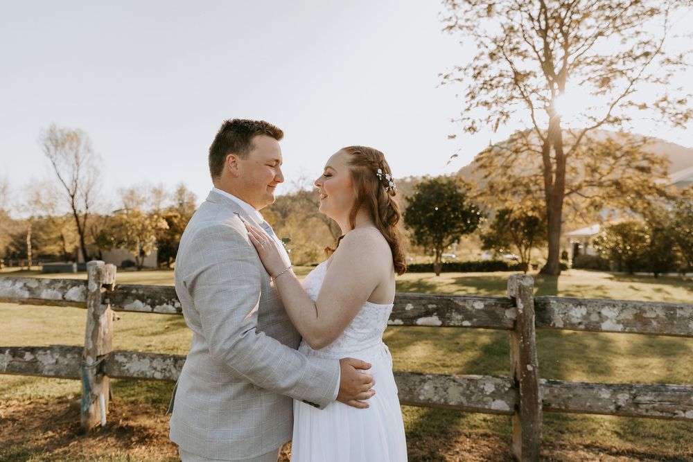 A romantic wedding couple shares tender moments in a sunlit autumn landscape during their outdoor photoshoot.