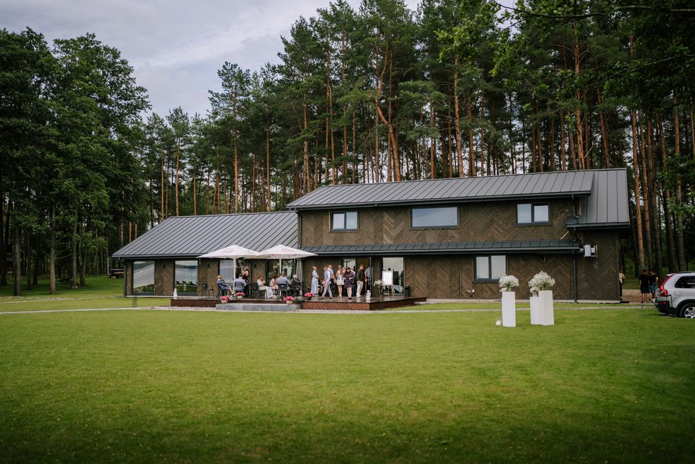 Panoramic view of a wedding venue surrounded by pine trees and green lawns.