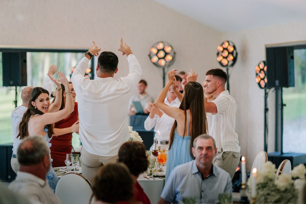 Wedding reception party with guests dancing and celebrating in an indoor venue.