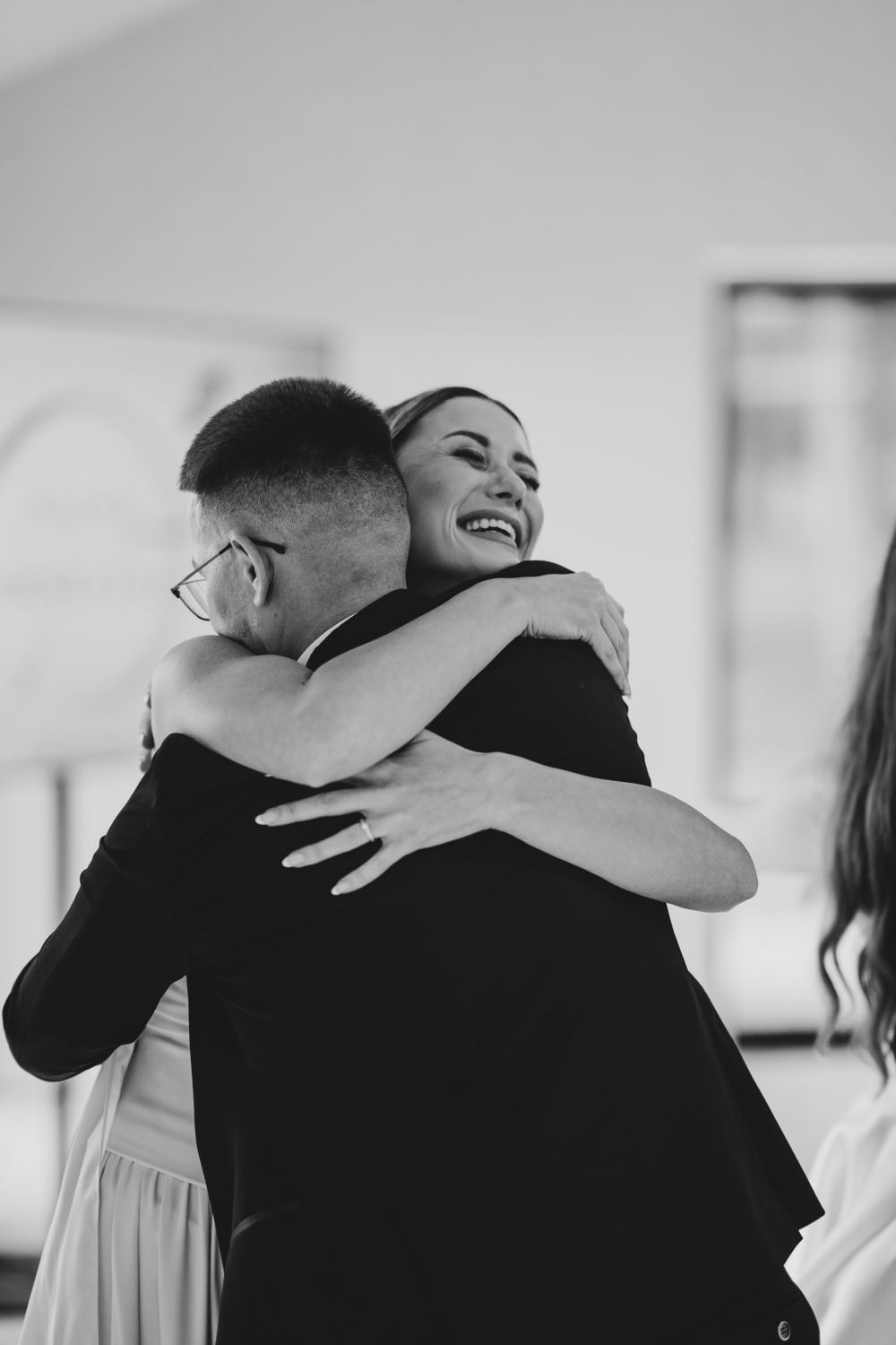 Black and white photograph of emotional embraces during wedding celebrations.