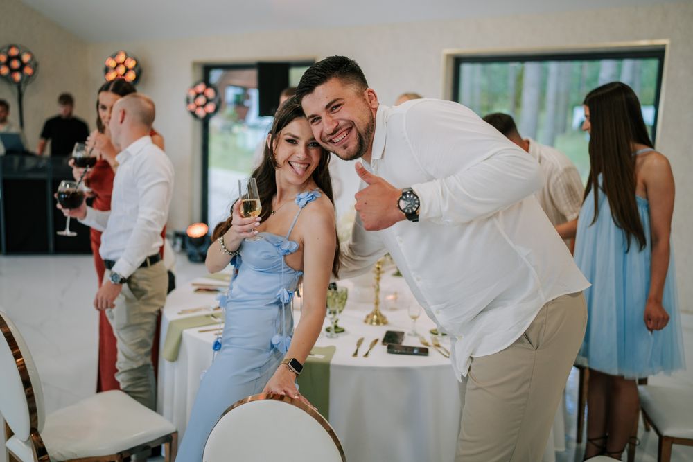 Wedding reception guests share joyful moments at an indoor celebration with festive decorations.