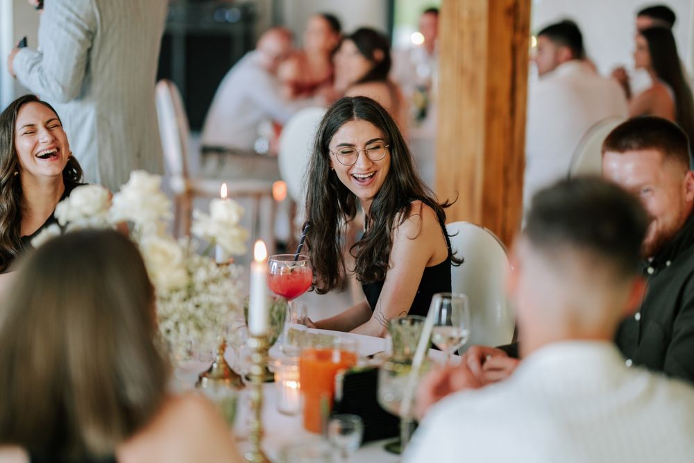 Guests enjoying lively conversation around an elegantly decorated dinner table with floral centerpieces.