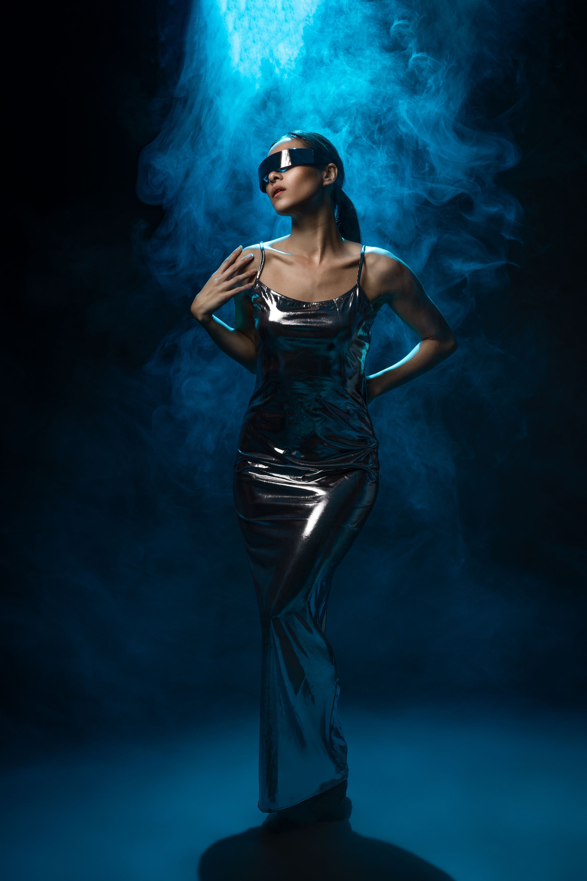 Dramatic fashion photo series of a person posing in dark clothing against blue smoke and lighting effects.