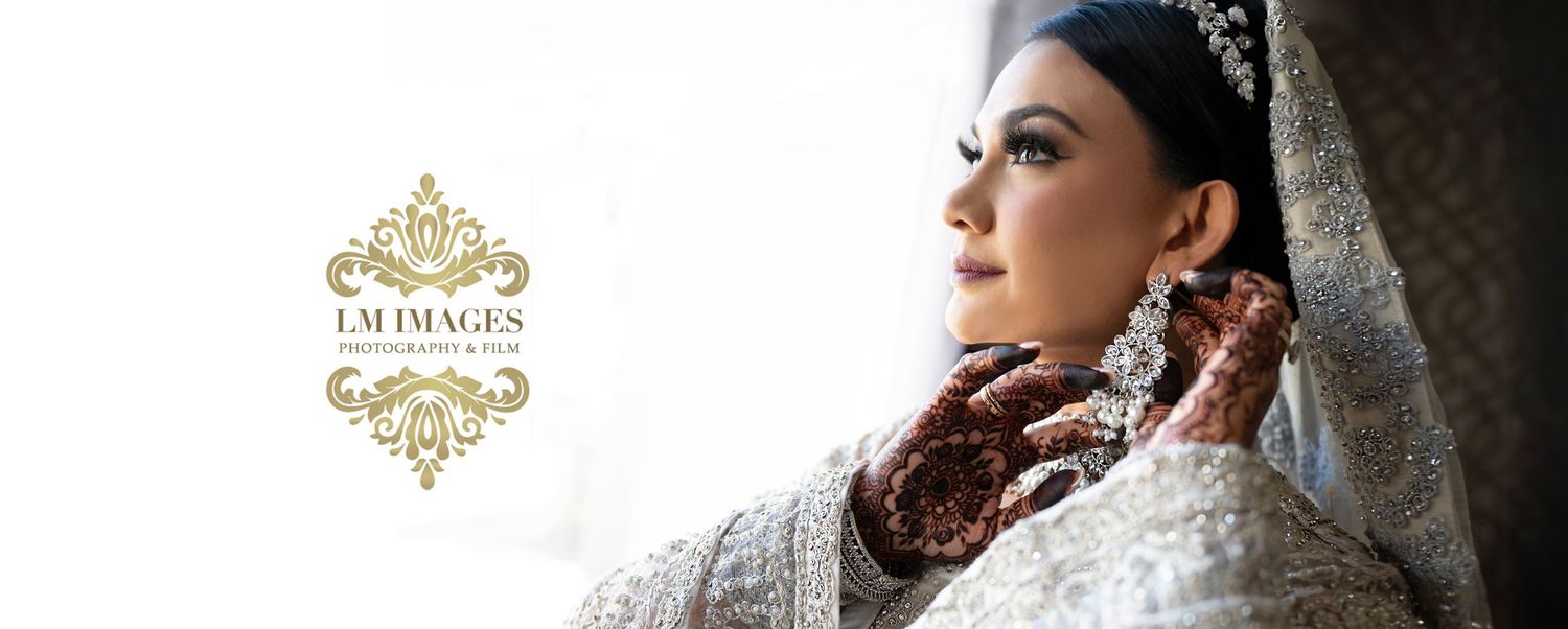 South Asian bride in traditional white bridal attire with ornate jewelry and henna adorned hands.