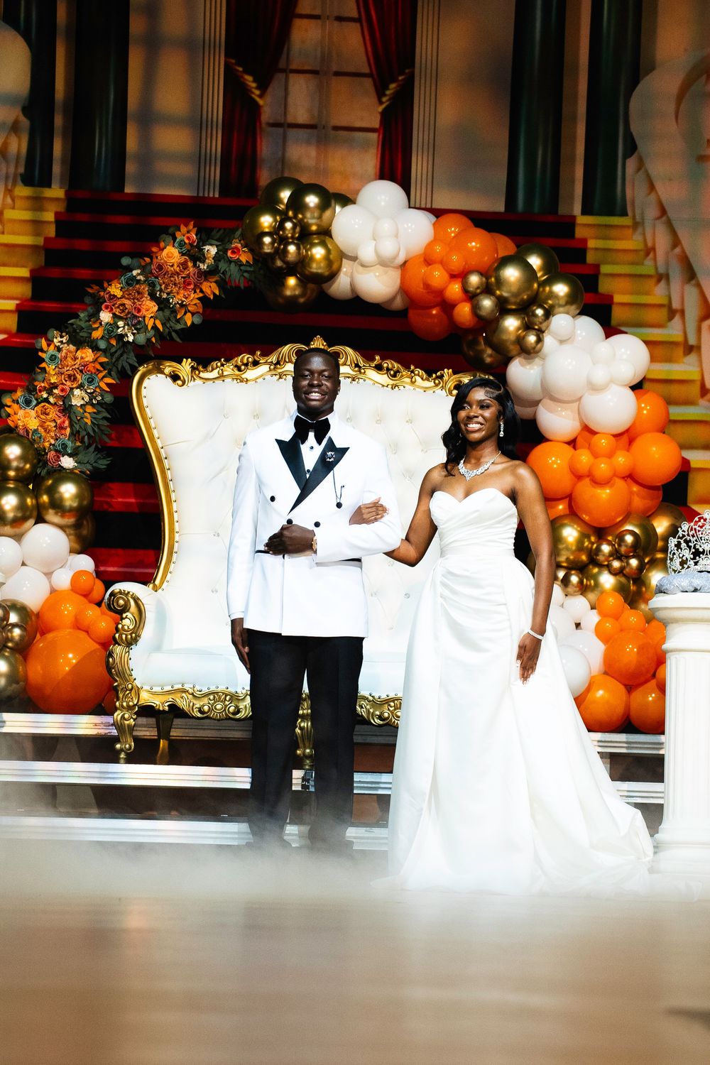 A wedding celebration with elegant balloon decor featuring orange and white balloons on grand staircase.
