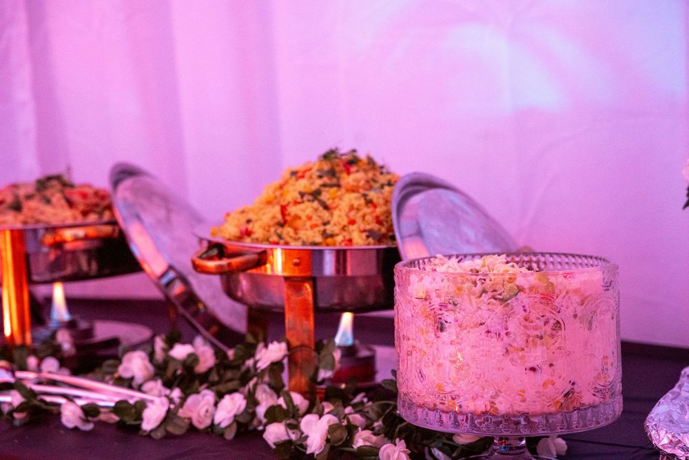 Pink and orange candy display with glass containers and scattered treats on a dark surface illuminated by purple lighting.