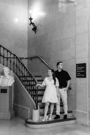 Four sequential black and white photos show people playfully posing on marble stairs in an elegant interior setting.
