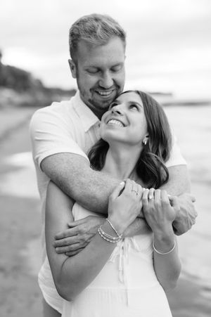 A couple shares an intimate black and white moment together on the beach.