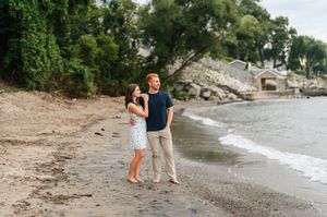 Couple walking together on a scenic beach shoreline during golden hour with waves gently lapping at the shore.