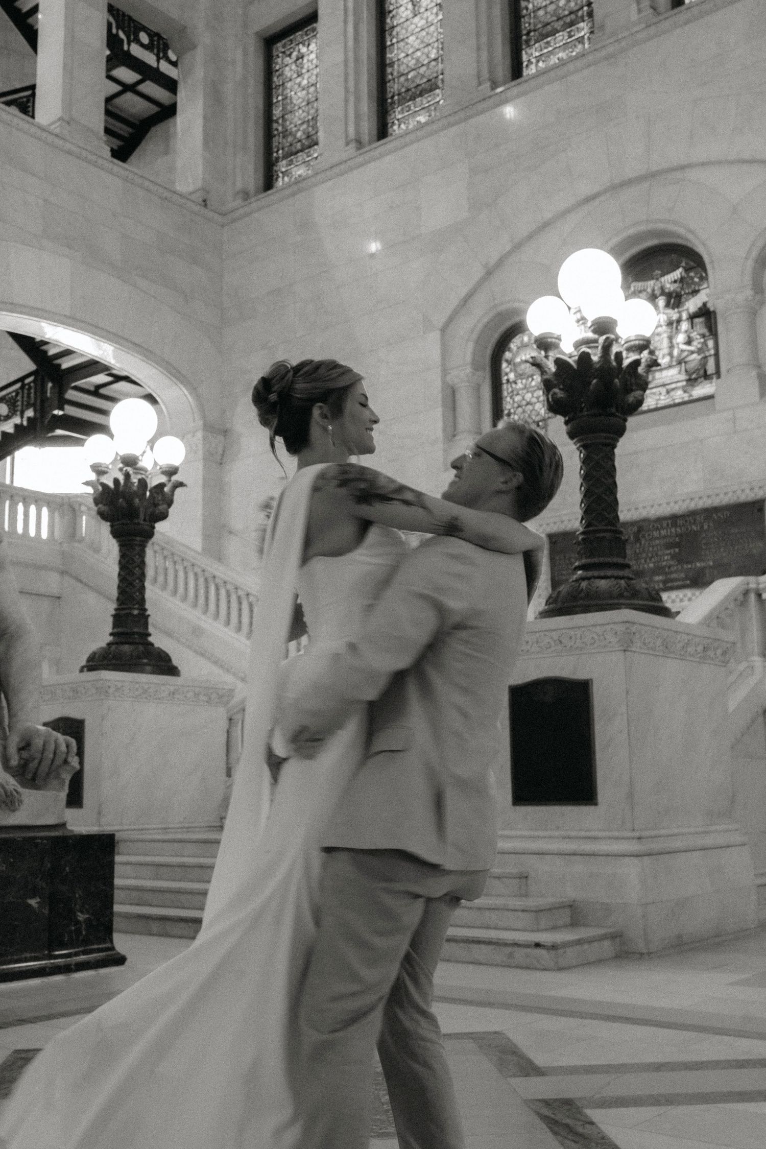 A black and white photo series showing a couple dancing together in an ornate marble building interior.