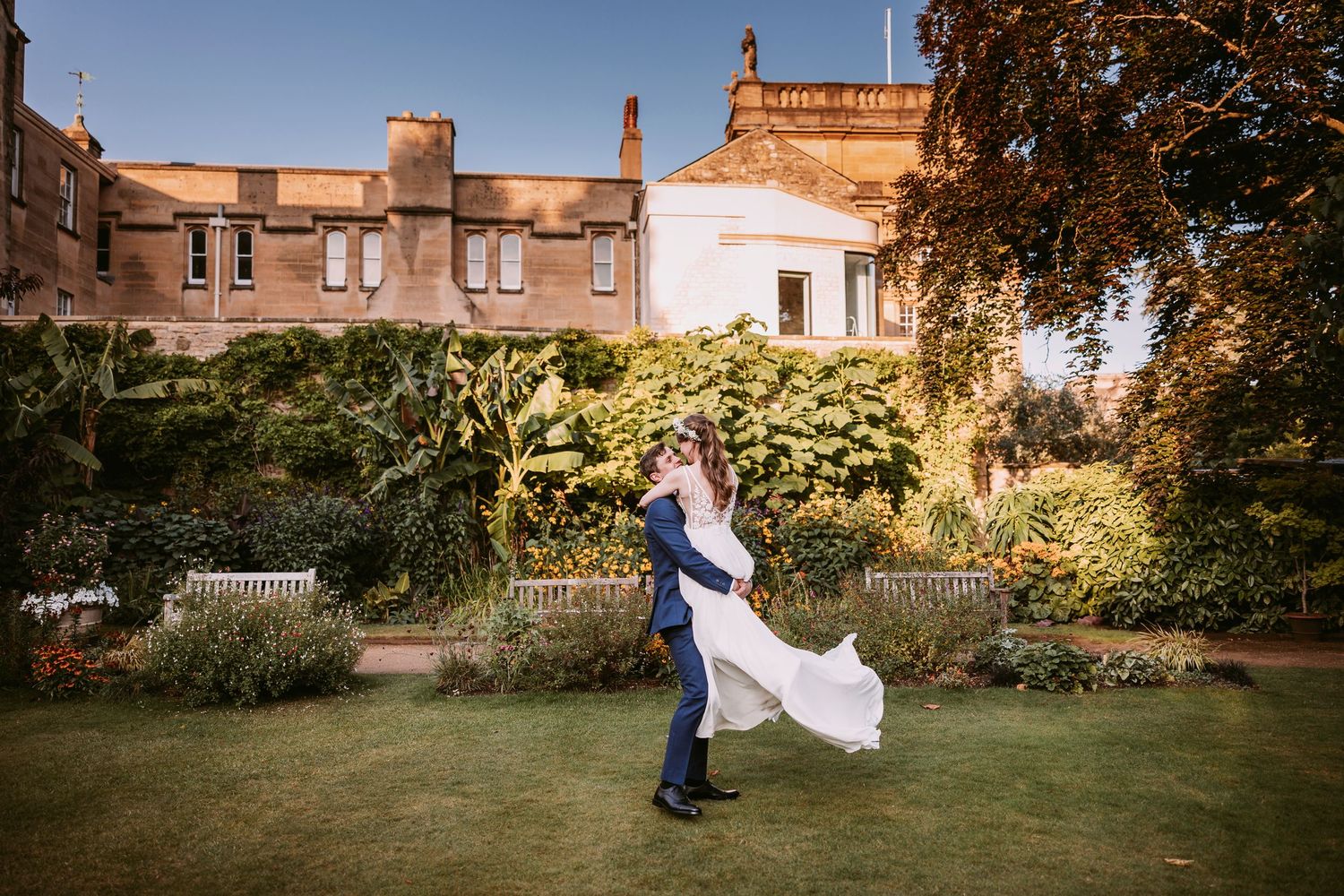 Wedding guests dance together in a garden setting during a sunset celebration.