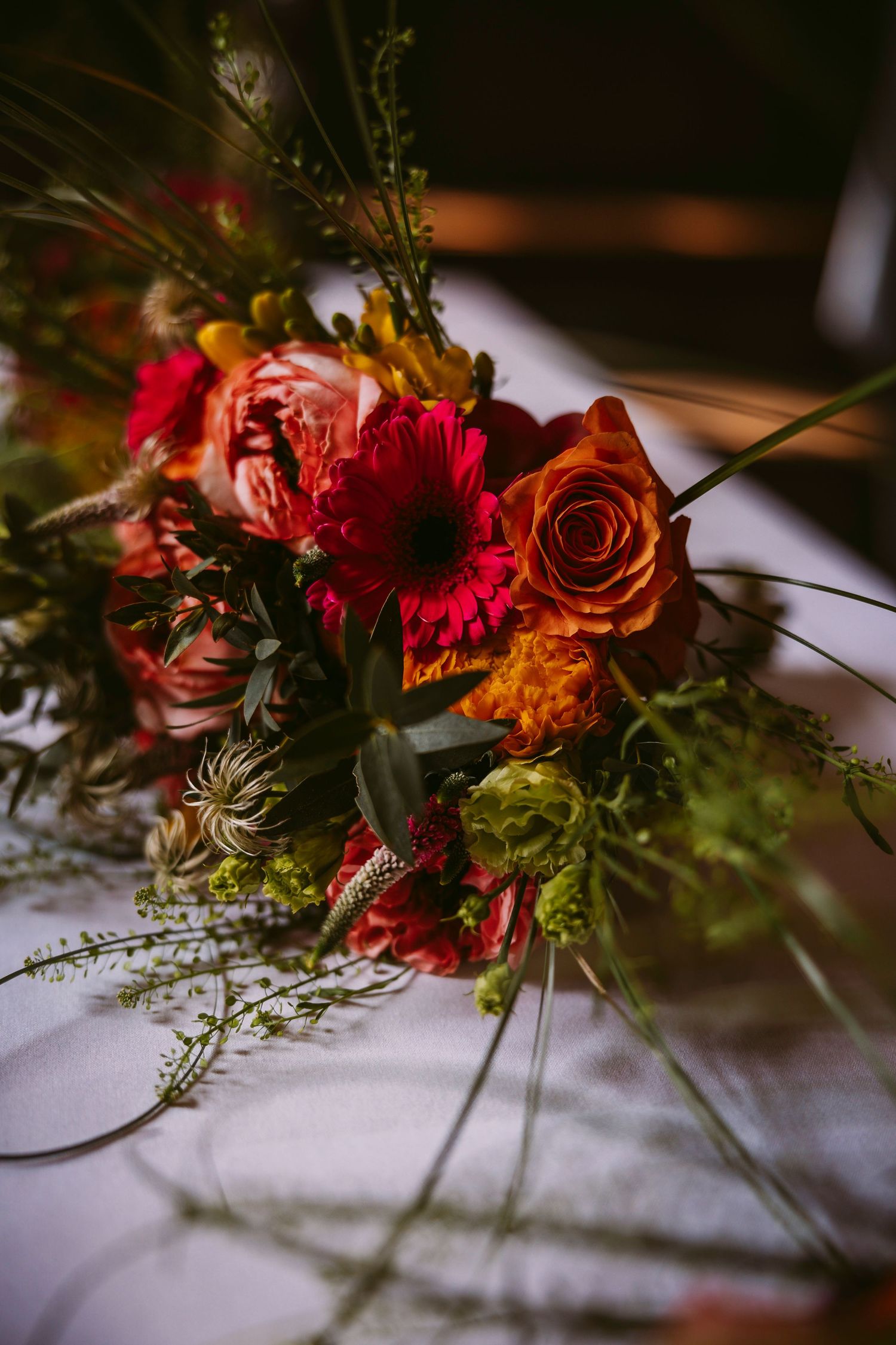 A series of elegant floral arrangements featuring vibrant red roses and greenery cast dramatic shadows on a white surface.