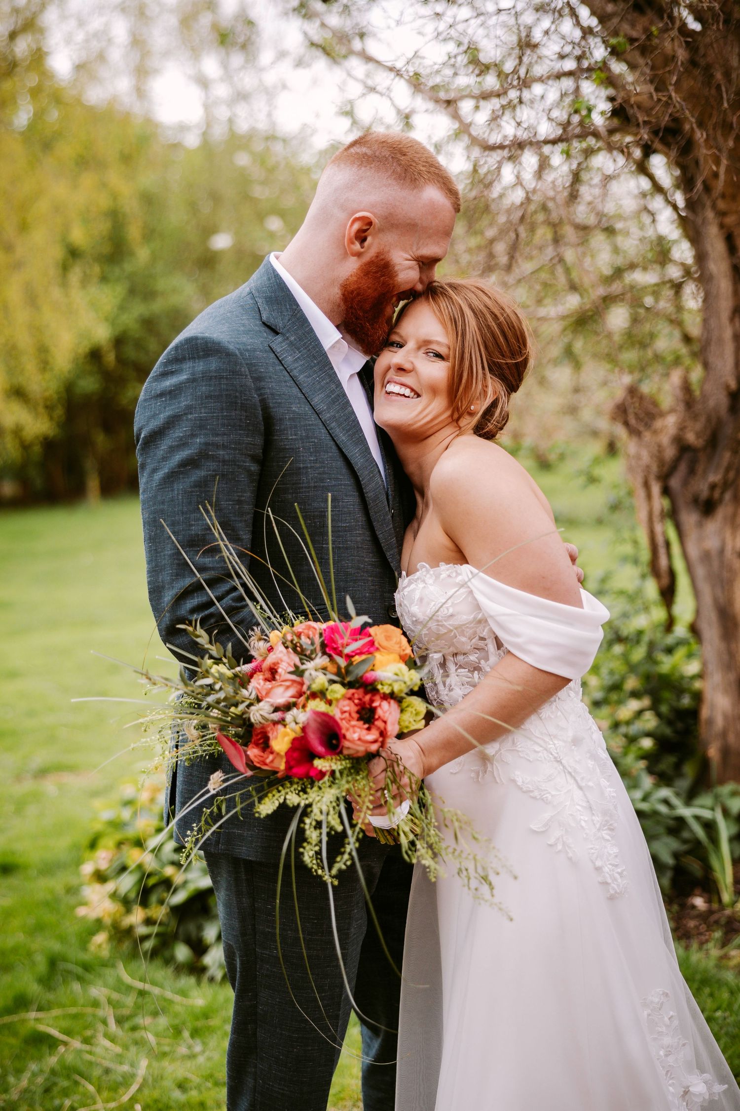 A romantic outdoor wedding moment with a beautiful bouquet of coral and peach flowers in a natural garden setting.