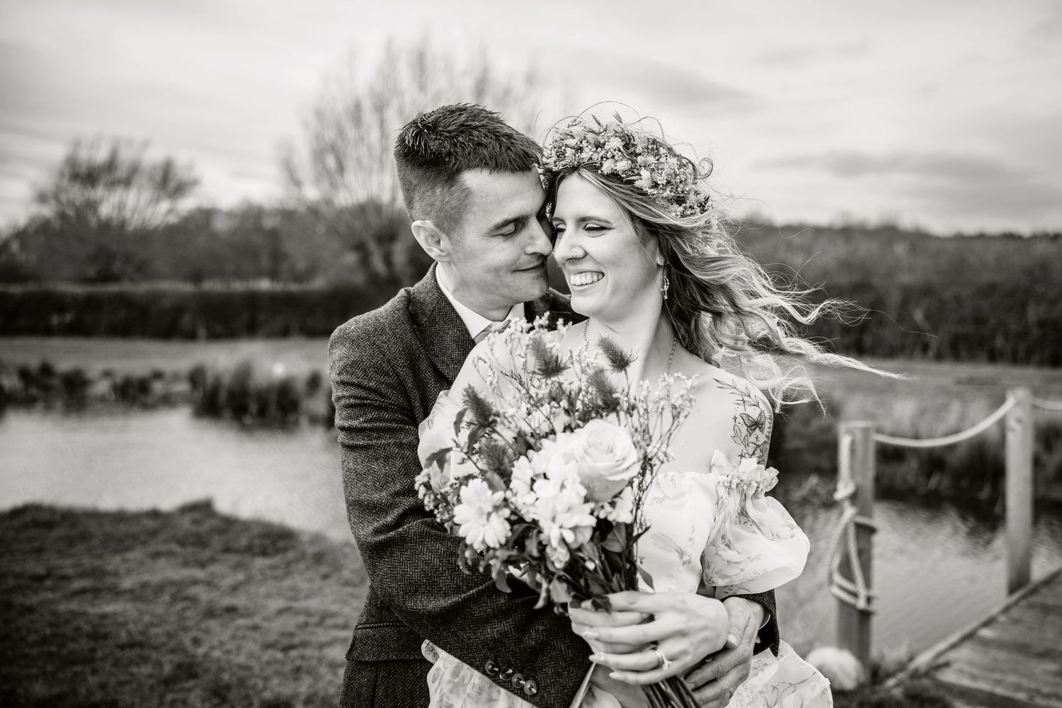 Black and white wedding photo showing couple embracing in outdoor garden setting with natural light.