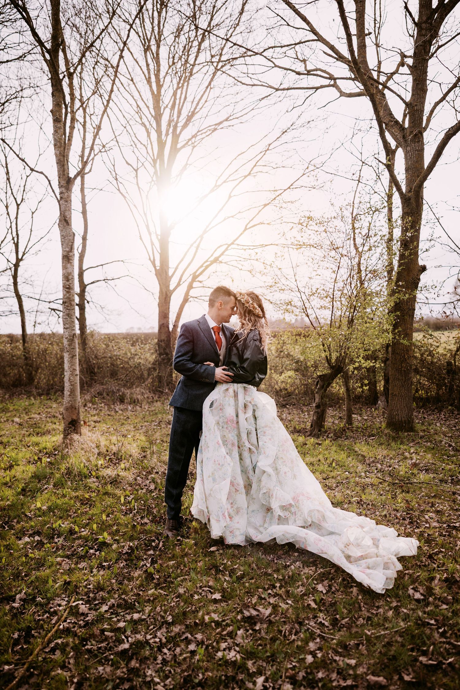 A romantic wedding photo sequence showing a couple in formal attire embracing among bare winter trees in a wooded area.