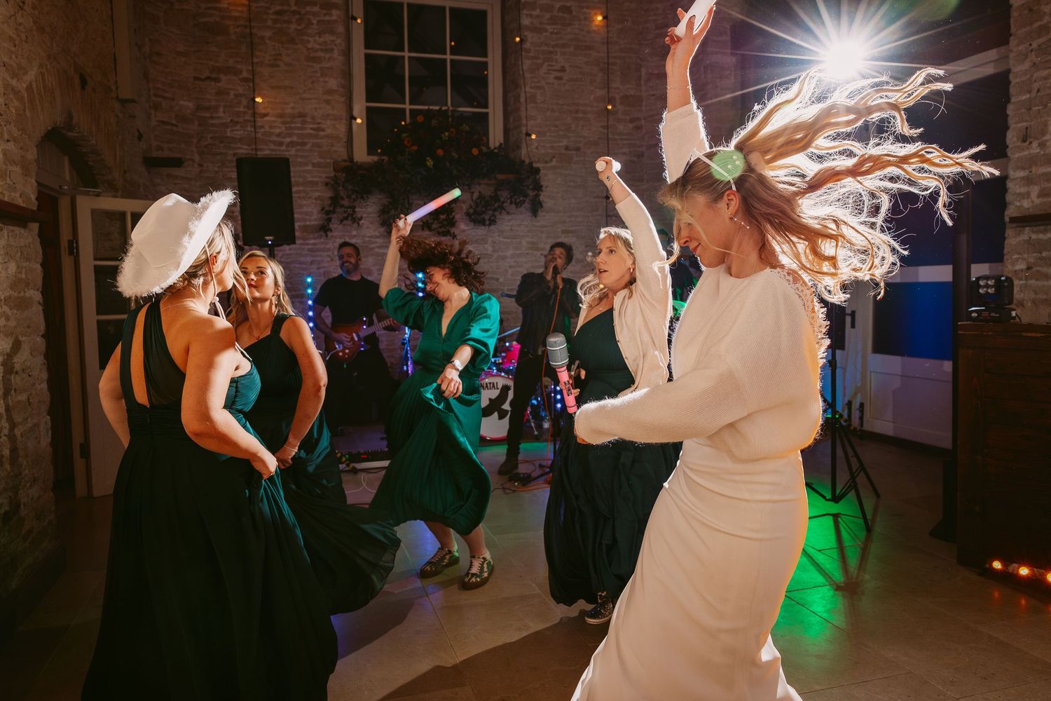 Wedding reception dance party with guests celebrating in a rustic brick venue with atmospheric lighting at Merriscourt wedding venue