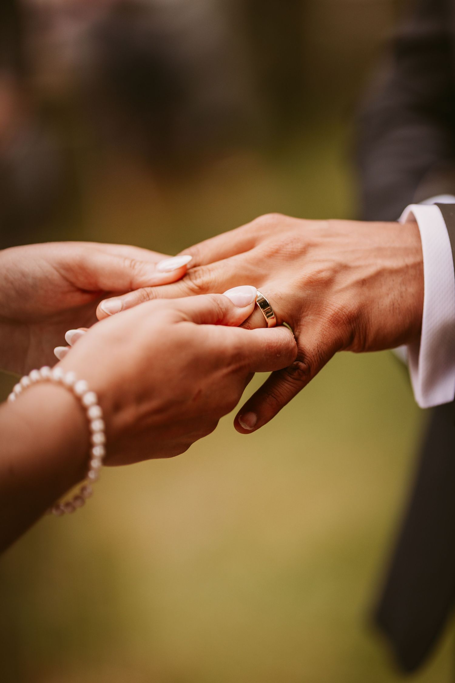 Close-up of hands exchanging wedding rings during a romantic ceremony.