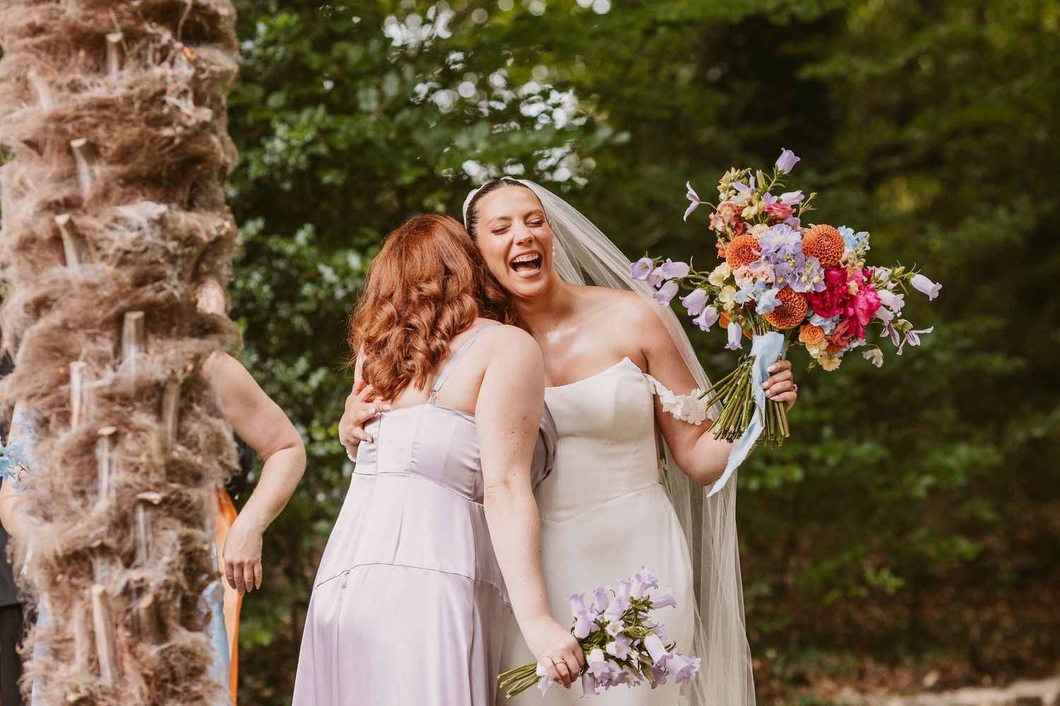 A wedding party celebrates joyfully under palm trees in a lush garden setting during a summer celebration.