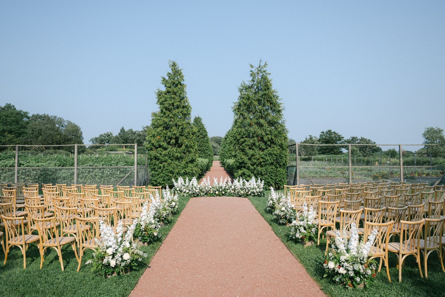 A historic brick building with white trim and cupola is shown from multiple angles surrounded by green trees and bushes. - Elawa Farm