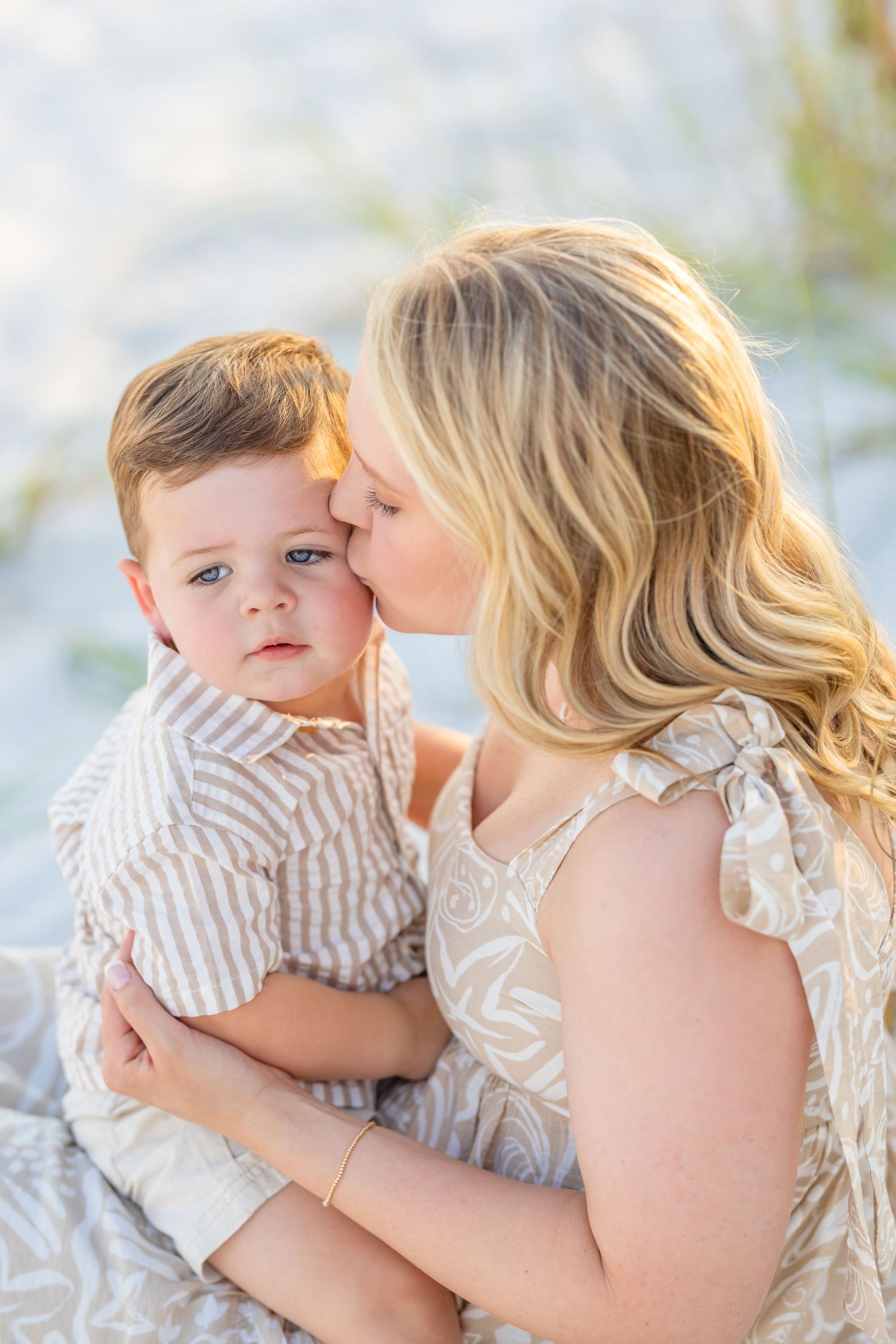 A tender moment captured in soft light showing affection and connection between parent and child in matching light-colored outfits.