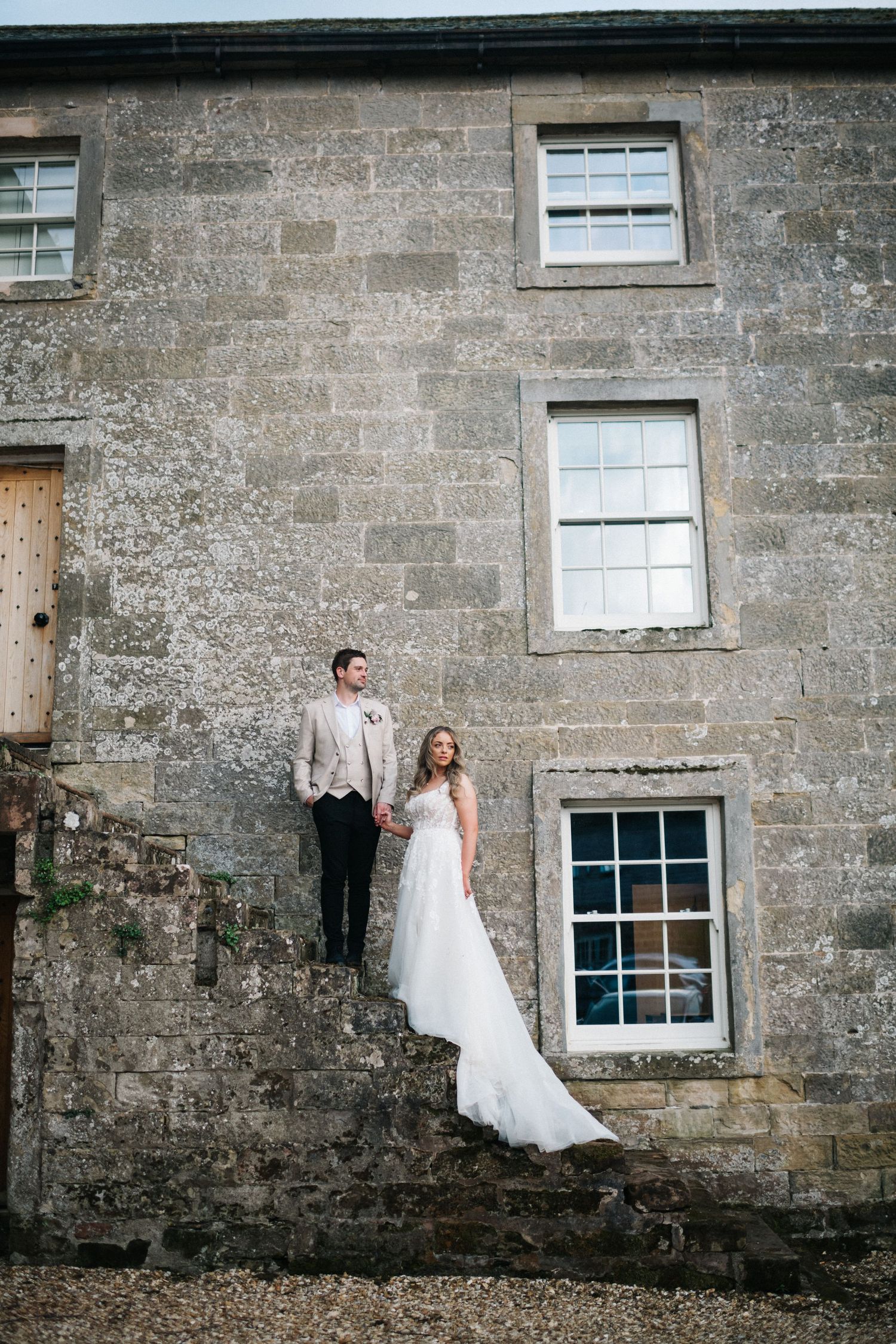 A series of four artistic wedding photos showing a bride posing against a rustic stone wall in a flowing white gown. Hidden River Cabins.