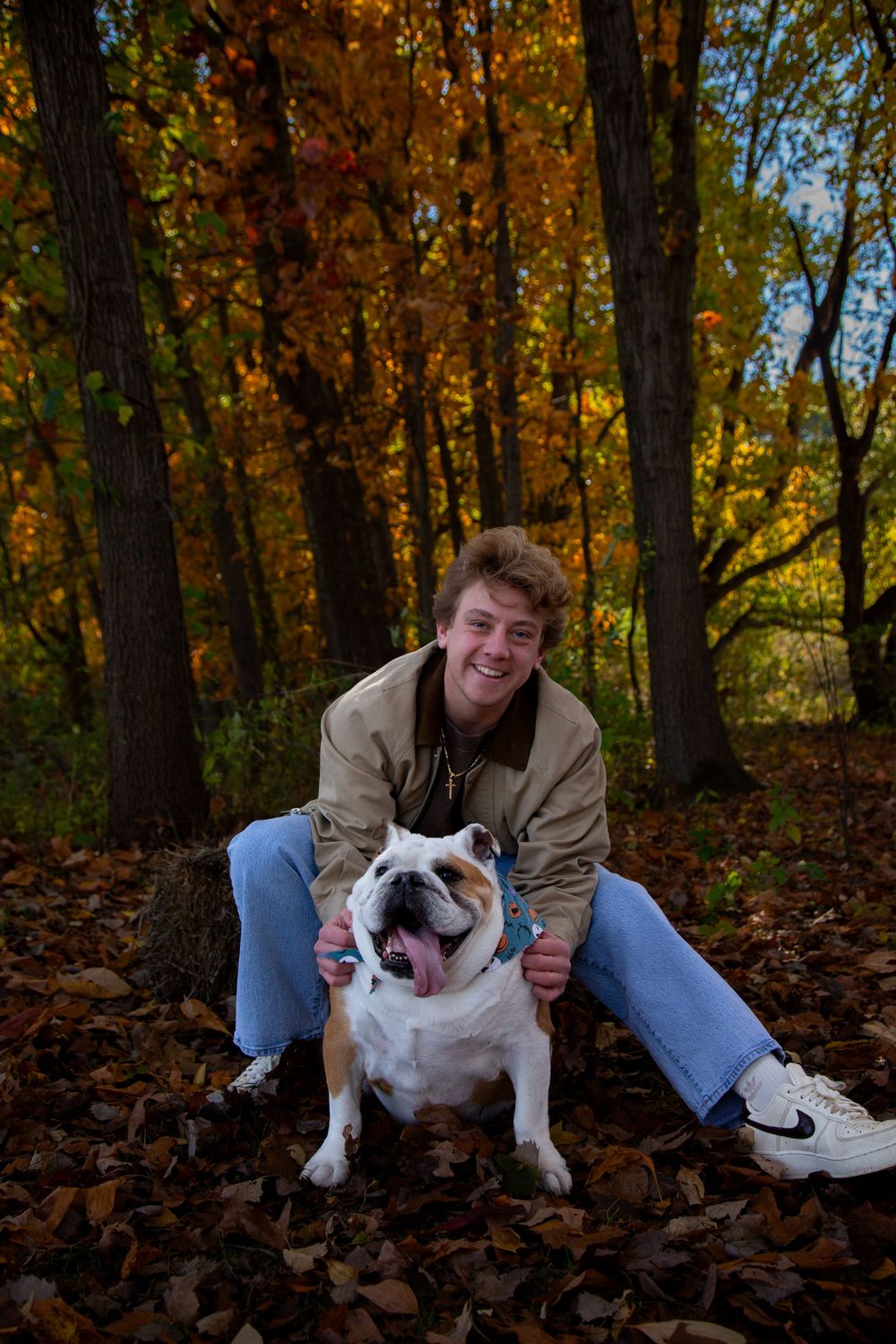 Michigan senior fall photo shoot in woods with bright true to color editing with his childhood dog