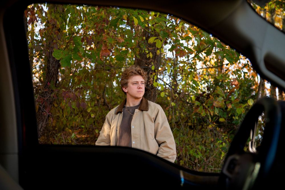 Michigan senior fall photo shoot in woods with bright true to color editing with his truck