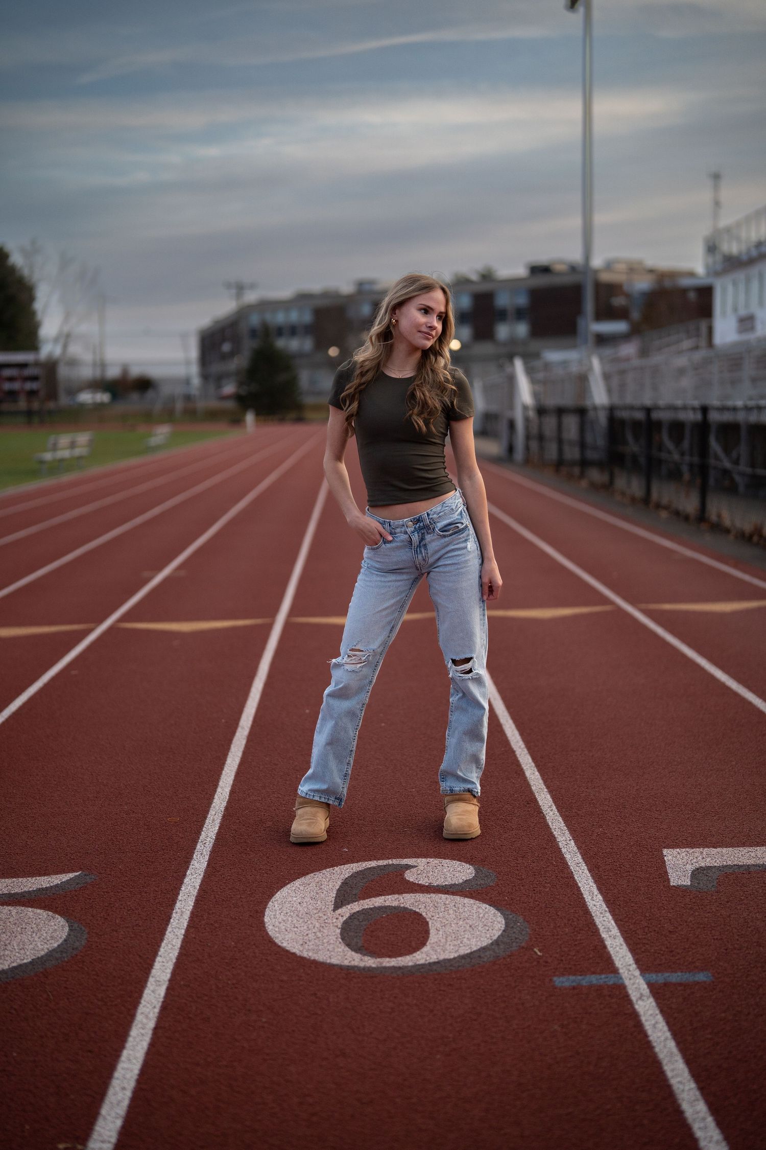 Creative portrait on a running track featuring casual denim and athletic setting.