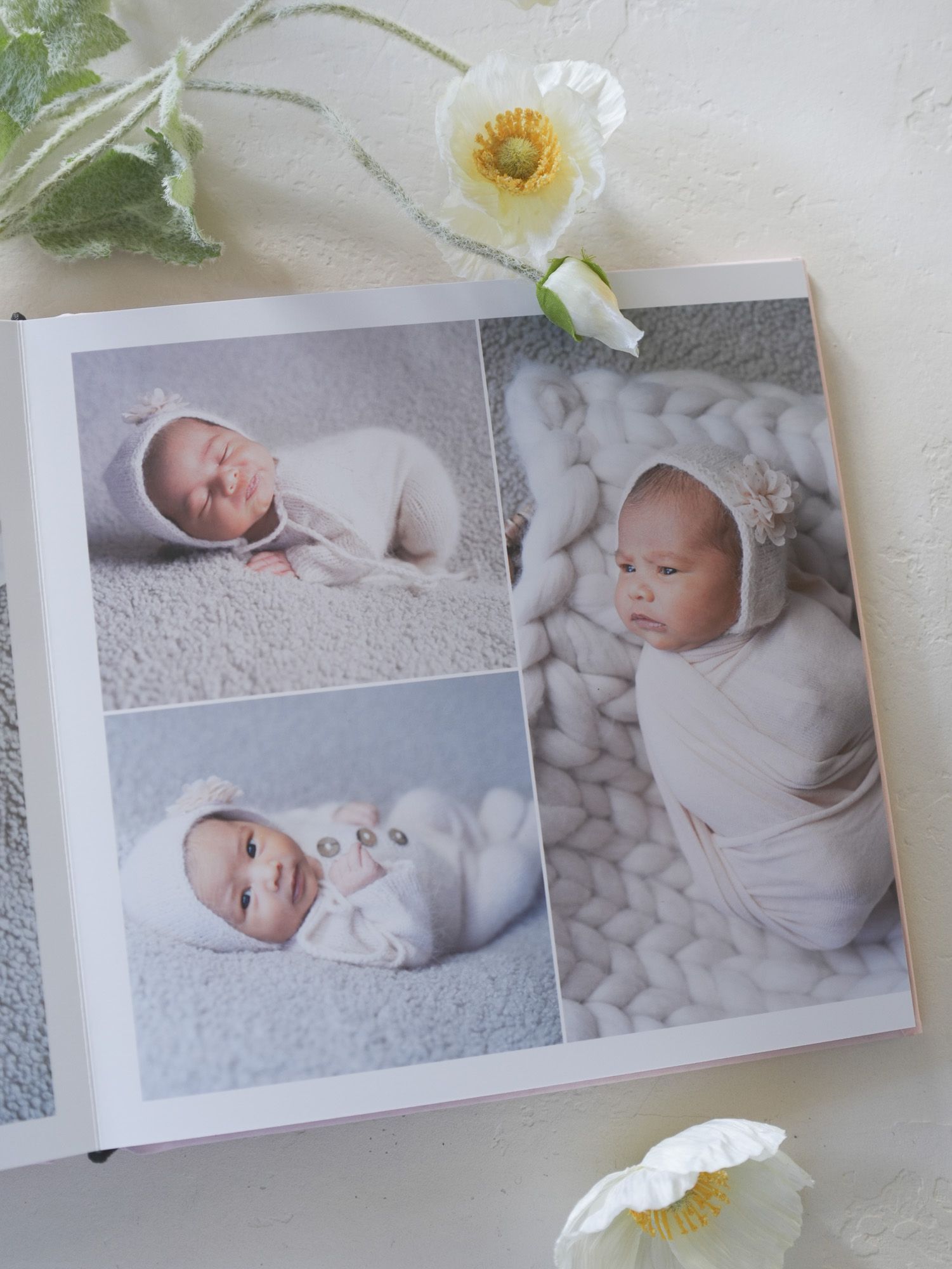 Newborn photography album page with infants wrapped in white against textured backgrounds.