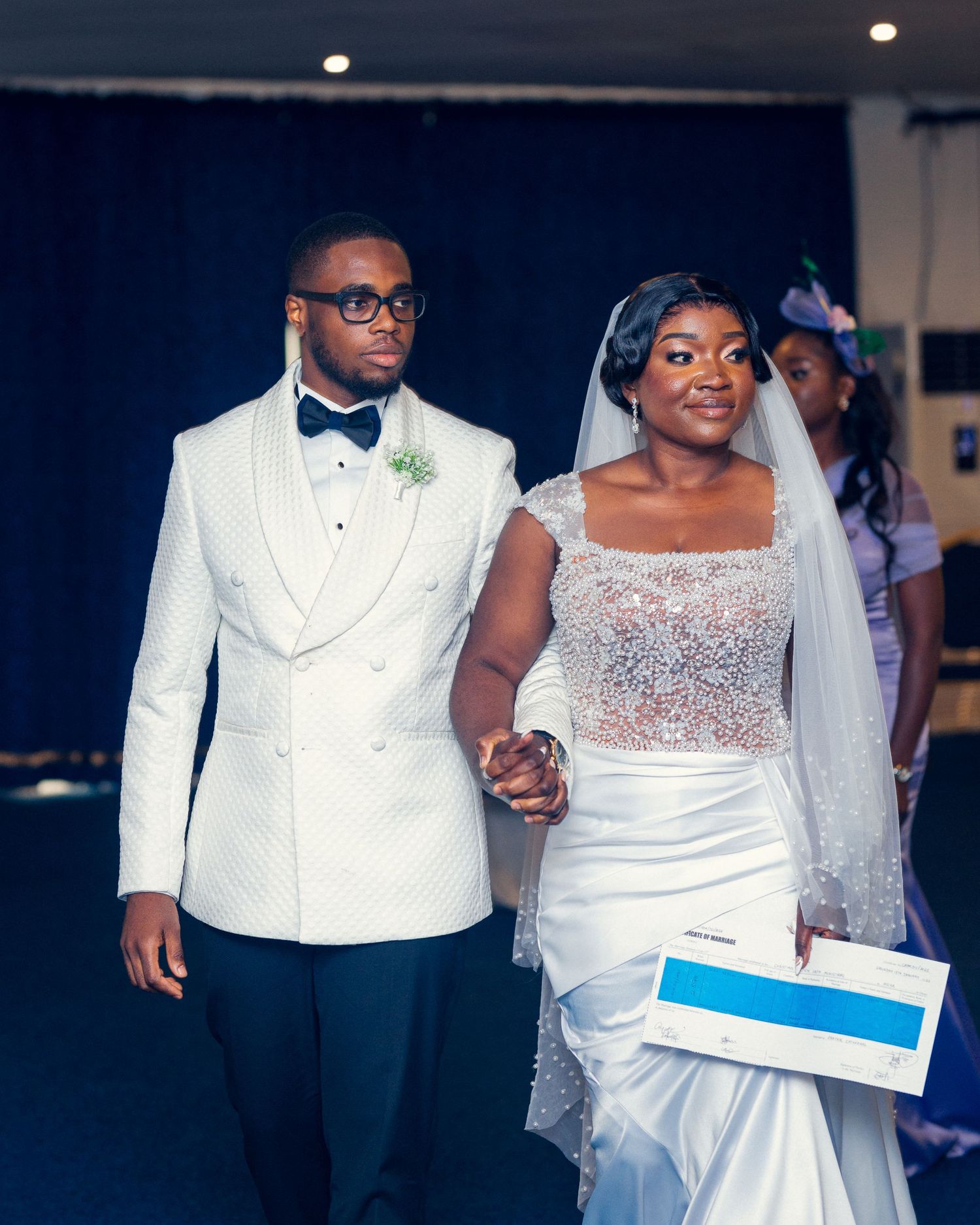Elegant couple in white wedding attire walk together during their ceremony.