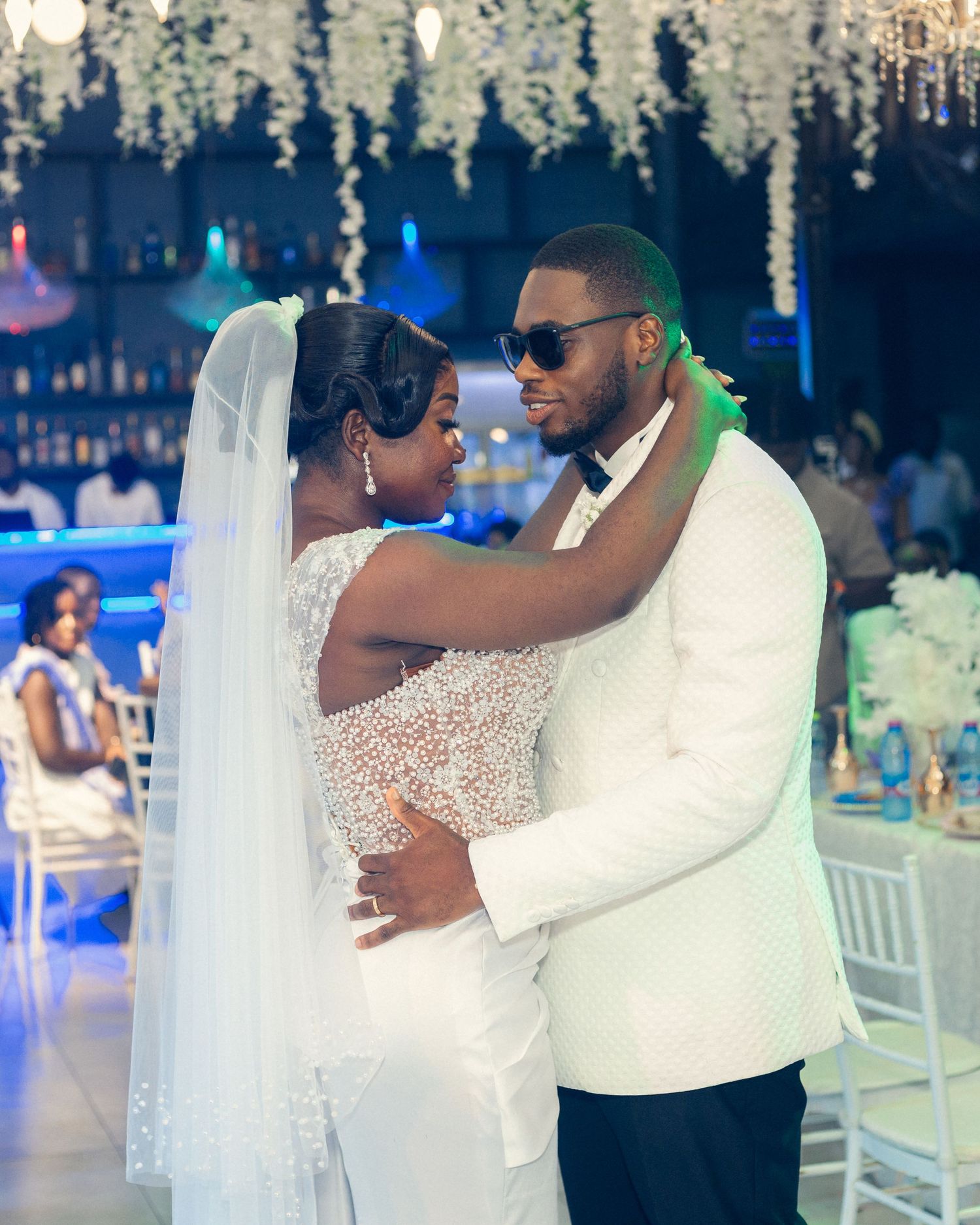Couple shares romantic dance moment under crystal chandeliers at elegant reception venue.