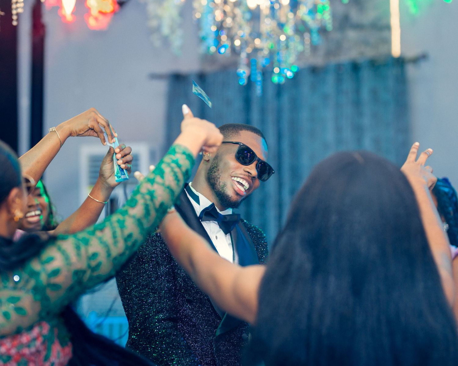 Celebrating party guests dancing and having fun under chandelier lighting.