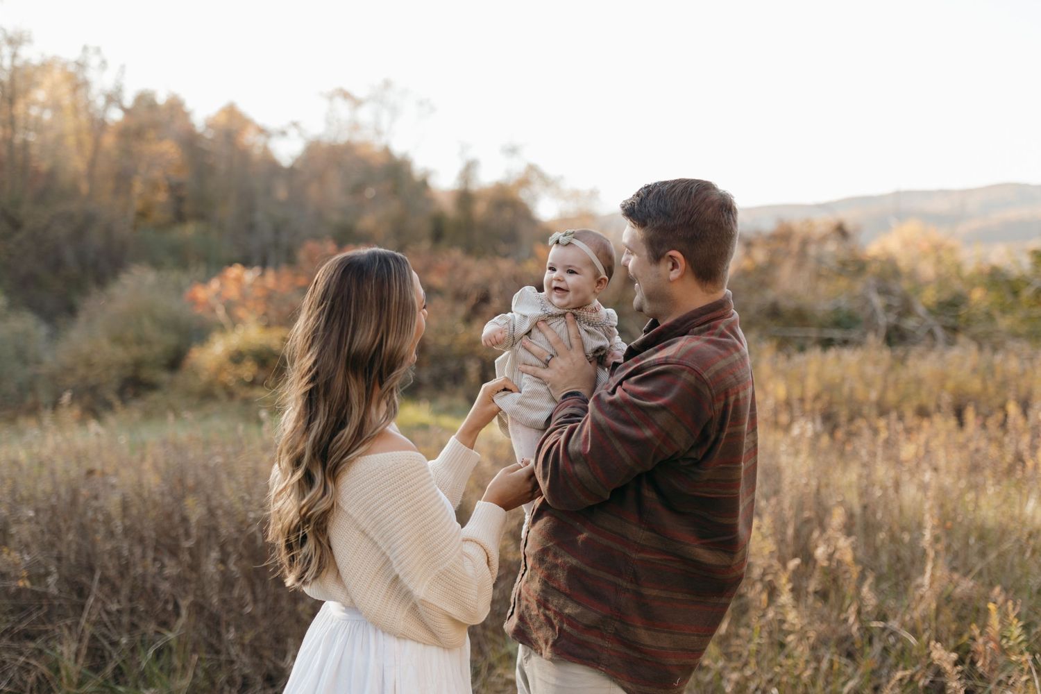 An intimate family portrait taken during sunset in a golden autumn field.