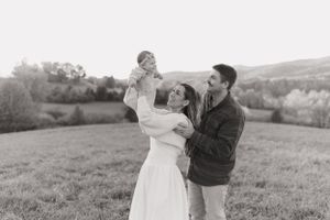 Black and white portrait of a joyful family moment in an open field.