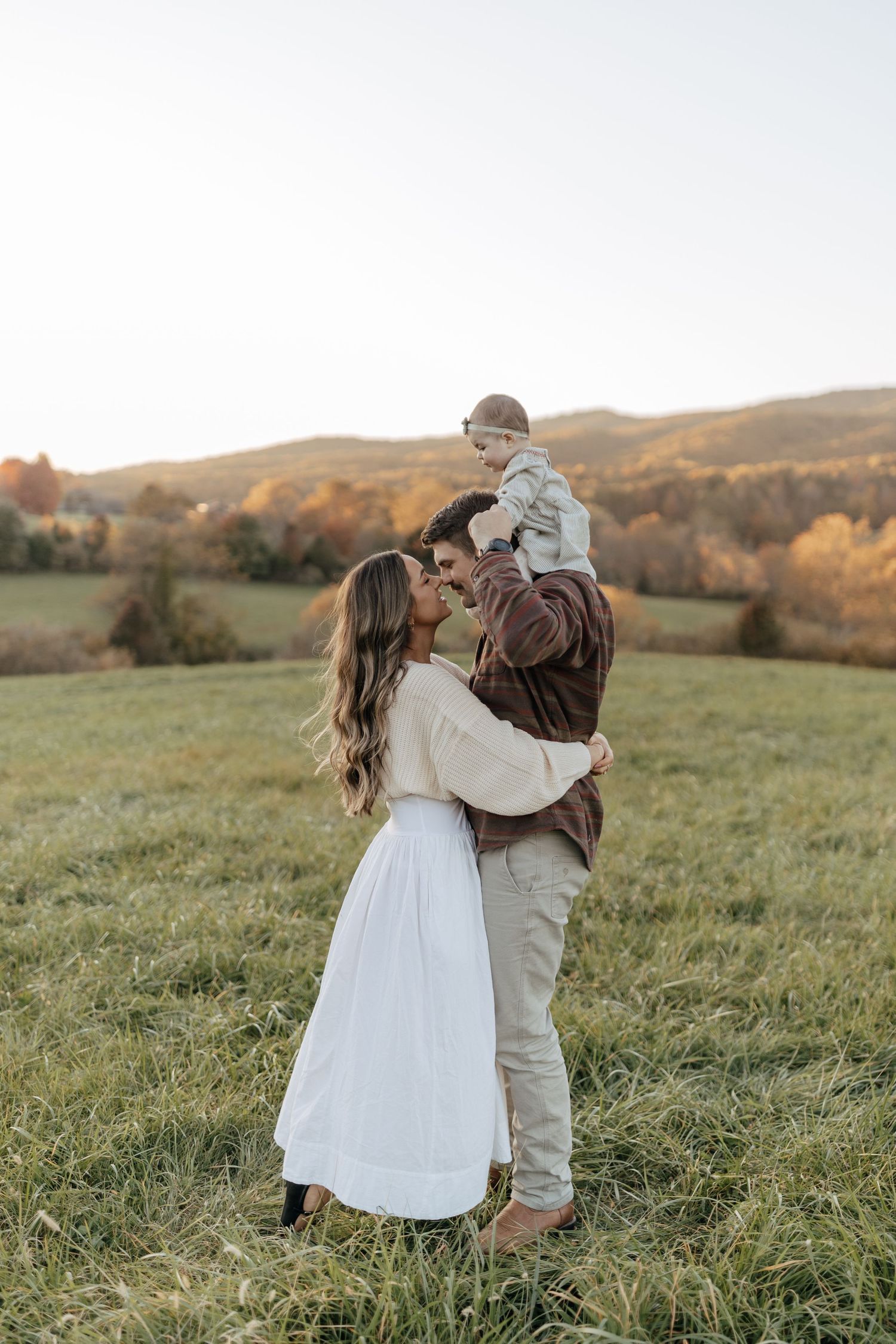A tender family portrait against rolling autumn hills during golden hour.