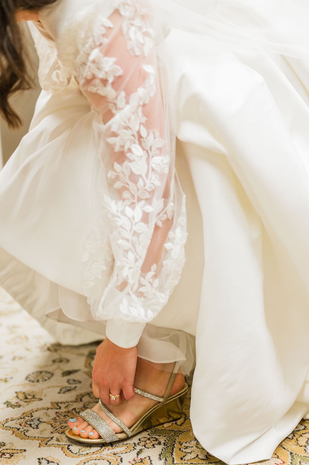 Bride puts on her shoes as she gets ready for her Bride Nuptial Traditional Latin Mass wedding at Holy Family Cathedral in Tulsa, Oklahoma.