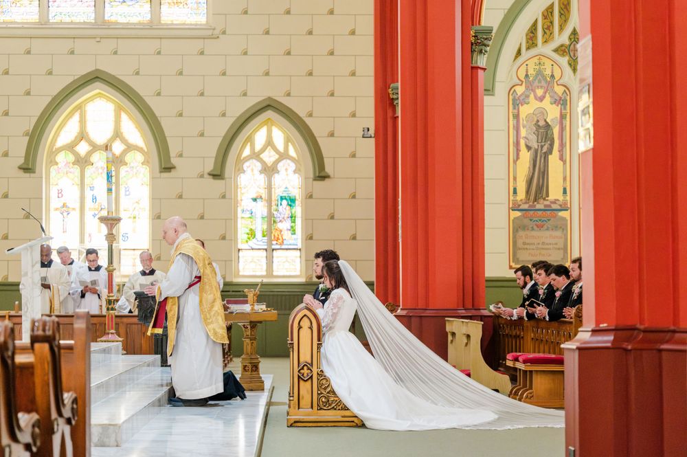Bride and groom kneeling during their Traditional Latin Mass wedding at Holy Family Cathedral in Tulsa, Oklahoma.