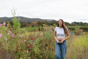 A serene meadow filled with pink wildflowers and tall grass against a backdrop of rolling hills in autumn.