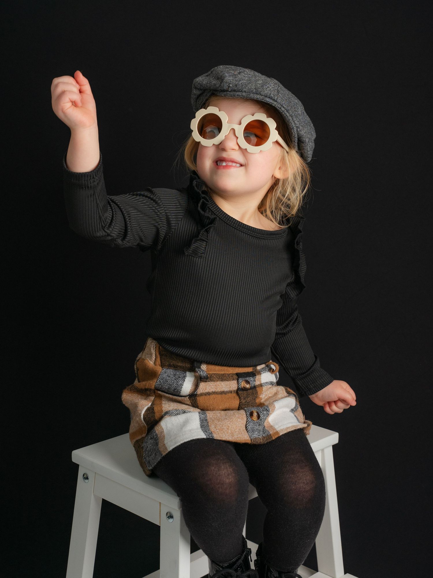 Picture of a little girl sitting on a white stool with pageboy hat and plaid skirt taken by East Tennessee children's photographer