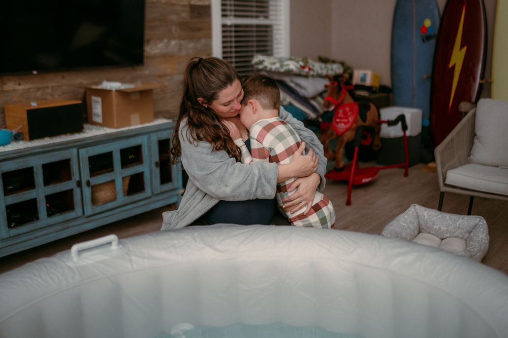 A parent and baby share a loving embrace while sitting on a couch in a cozy living room.