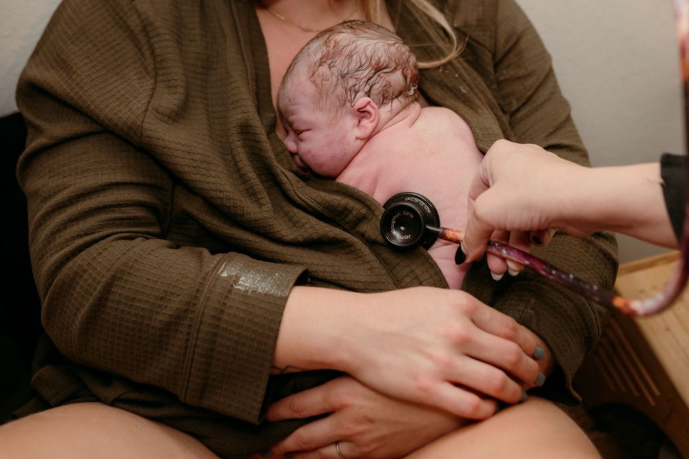 Healthcare provider examining newborn baby with stethoscope during medical checkup.