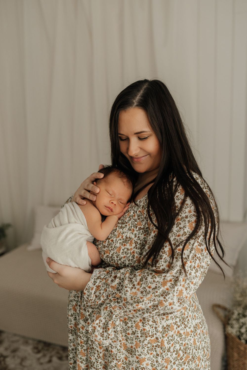 A heartwarming moment of mother and newborn sharing an intimate embrace in a floral dress.