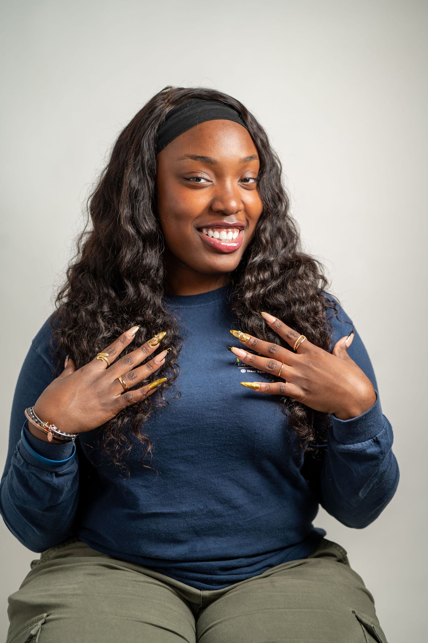 “A confident woman with long curls and well-manicured nails, smiling and looking off-camera in a professional portrait session. Clean, edito