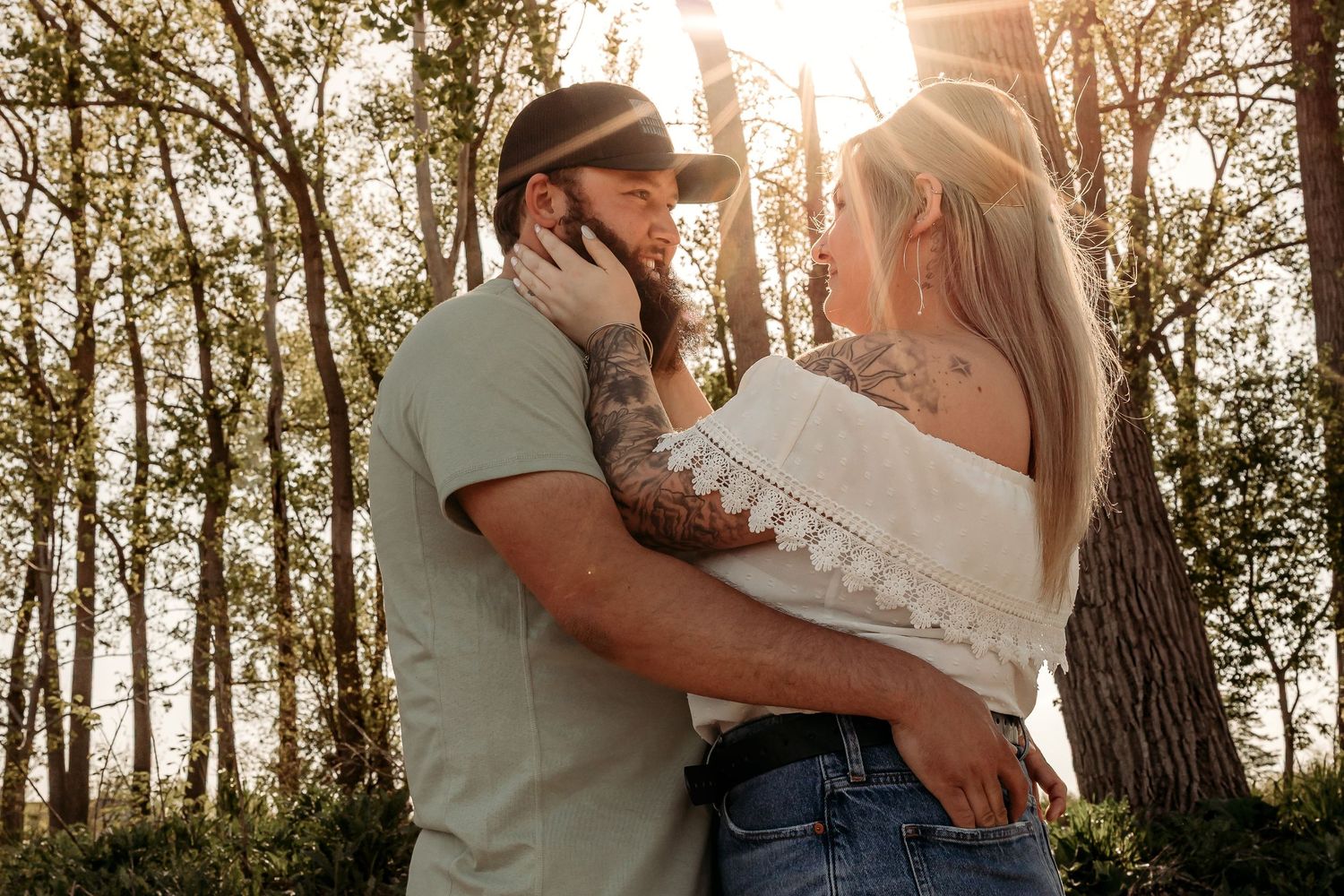 Couple sharing intimate moment among pine trees during fall engagement photoshoot.
