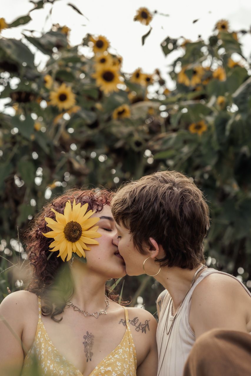 A tender moment captured between a couple among blooming sunflowers.