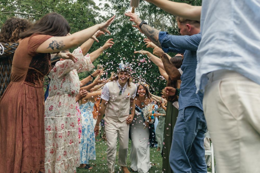 Wedding guests form a tunnel with raised arms during an outdoor celebration.